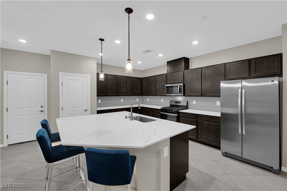 Modern kitchen w/ex-large quartz countertops, island w/breakfast bar, espresso cabinets, pendant lights, SS appliances, tile floors & pantry.
