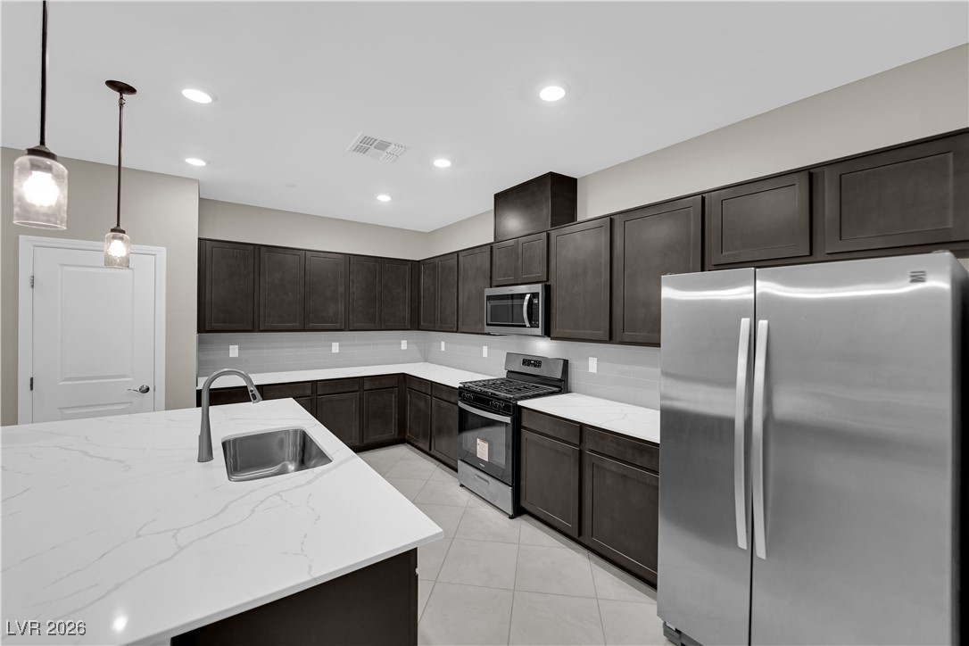 2606 Ercolano Street Henderson, NV 89044 - Photo 12 of 46 Modern kitchen w/ex-large quartz countertops, island w/breakfast bar, espresso cabinets, pendant lights, SS appliances, subway tile backsplash, tile floors & pantry.