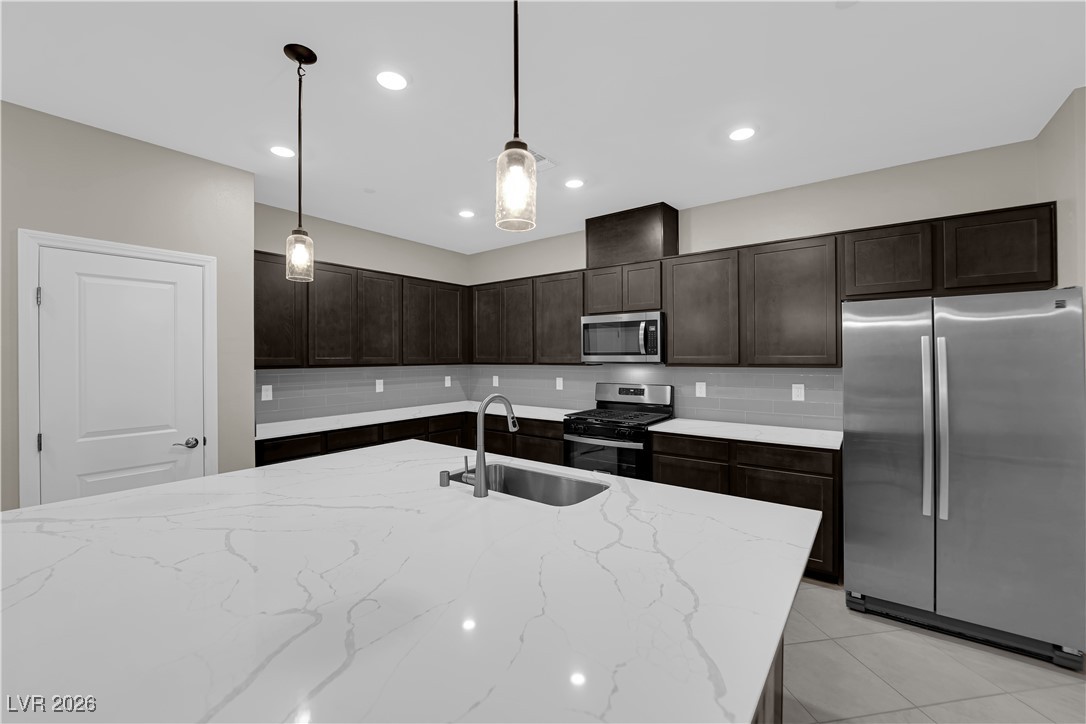 2606 Ercolano Street Henderson, NV 89044 - Photo 13 of 46 Modern kitchen w/ex-large quartz countertops, island w/breakfast bar, espresso cabinets, pendant lights, SS appliances, subway tile backsplash, tile floors & pantry.