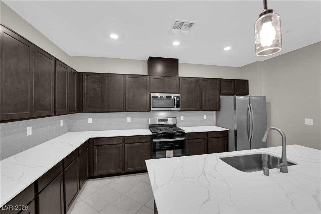 2606 Ercolano Street Henderson, NV 89044 - Photo 14 of 46 Modern kitchen w/ex-large quartz countertops, island w/breakfast bar, espresso cabinets, pendant lights, SS appliances, subway tile backsplash, tile floors & pantry.