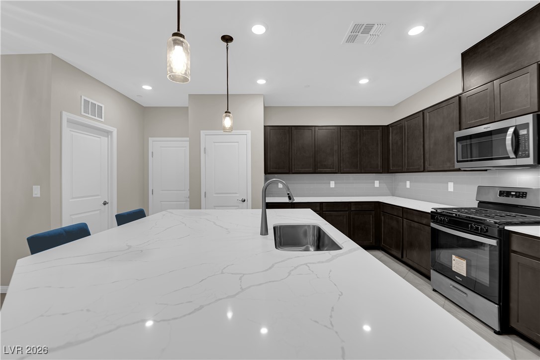 2606 Ercolano Street Henderson, NV 89044 - Photo 15 of 46 Modern kitchen w/ex-large quartz countertops, island w/breakfast bar, espresso cabinets, pendant lights, SS appliances, subway tile backsplash, tile floors & pantry.