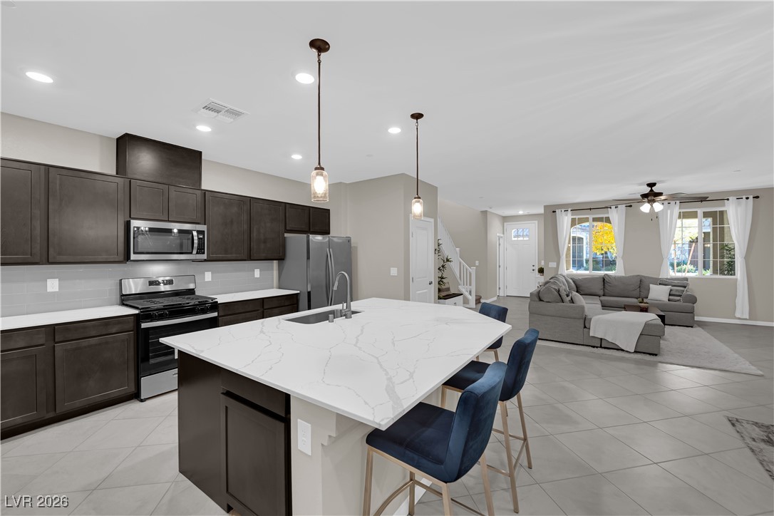 2606 Ercolano Street Henderson, NV 89044 - Photo 17 of 46 Modern kitchen w/ex-large quartz countertops, island w/breakfast bar, espresso cabinets, pendant lights, SS appliances, subway tile backsplash, tile floors & pantry.