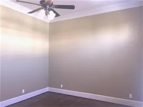 an empty room with a chandelier fan and wooden floor