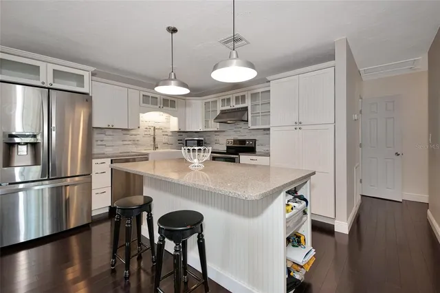 a kitchen with kitchen island white cabinets and stainless steel appliances