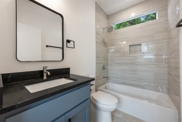 a bathroom with a bathtub sink vanity mirror and toilet