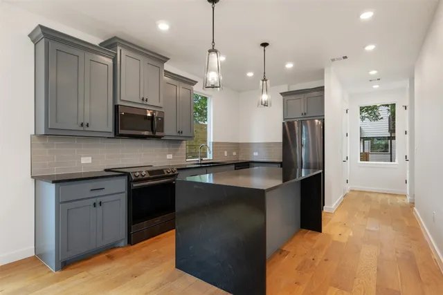 a kitchen with stainless steel appliances granite countertop a sink a stove and a refrigerator