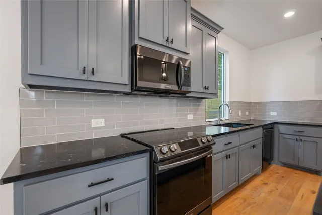 a kitchen with stainless steel appliances granite countertop white cabinets and a stove top oven