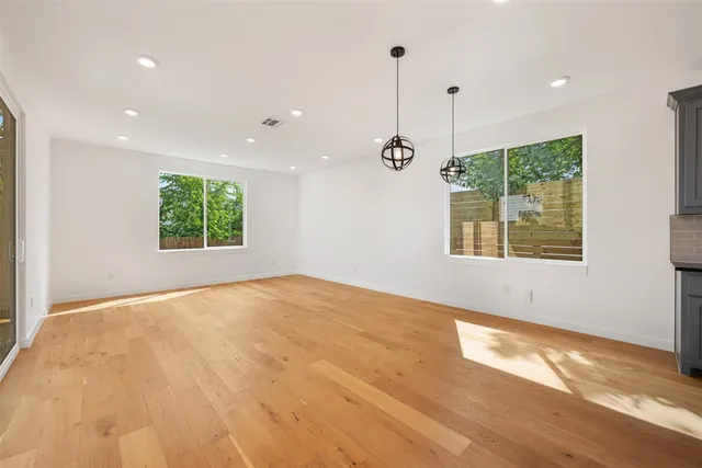 a view of an empty room with a window and wooden floor