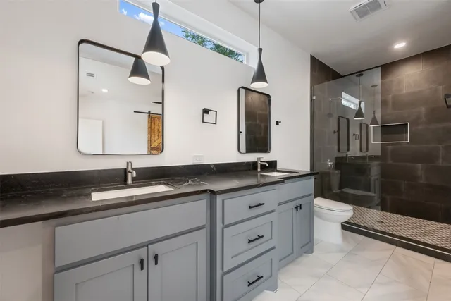 a bathroom with a granite countertop sink a toilet a mirror and shower