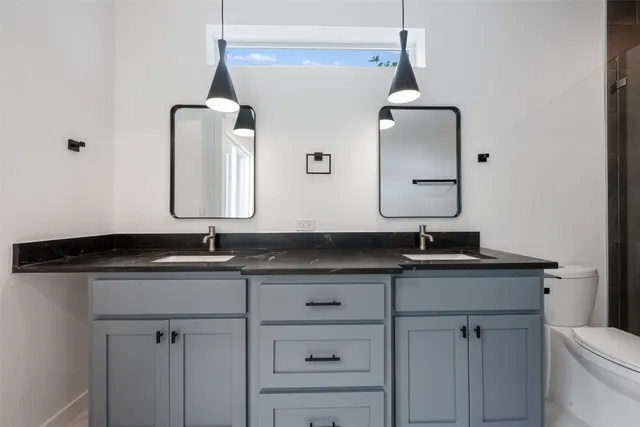 a bathroom with a granite countertop sink a large mirror and a toilet
