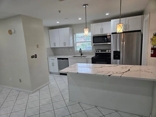 a kitchen with kitchen island a counter top space appliances and cabinets
