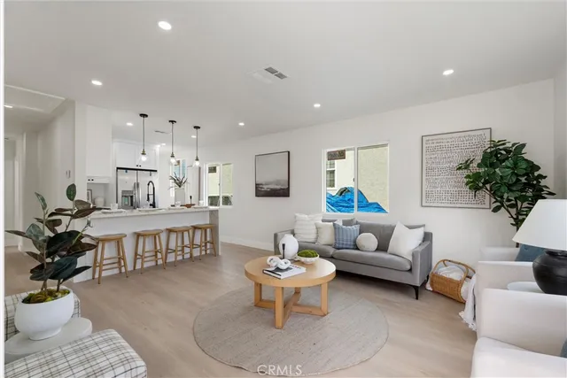 a living room with furniture and a dining room with wooden floor