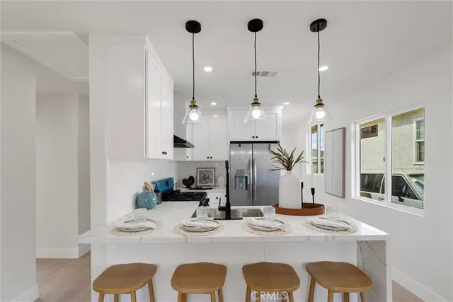 a view of kitchen with stainless steel appliances kitchen island granite countertop a stove a sink a dining table and chairs with wooden floor