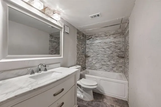 a bathroom with a granite countertop sink a toilet and shower