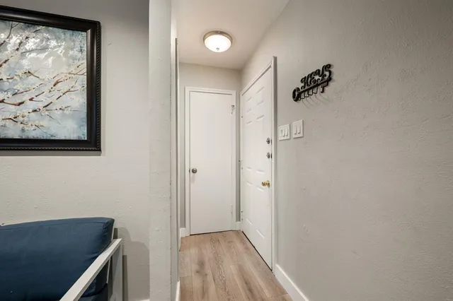 a view of hallway with window and wooden floor