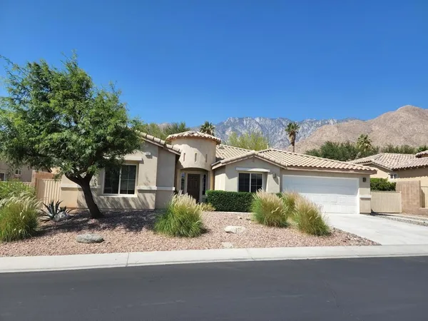 a front view of a house with a garden and mountain view