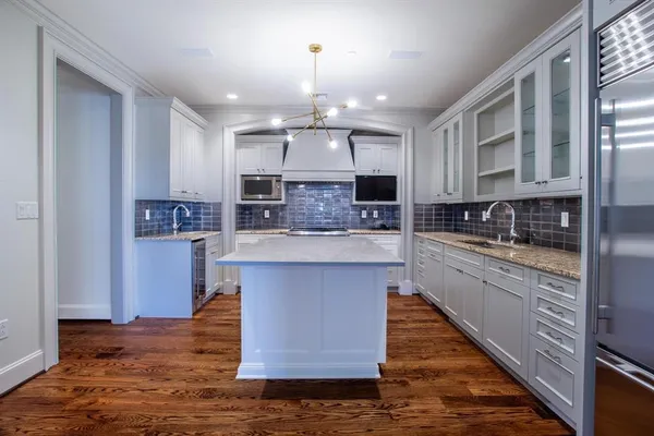 a large kitchen with stainless steel appliances kitchen island granite countertop a table chairs sink and cabinets