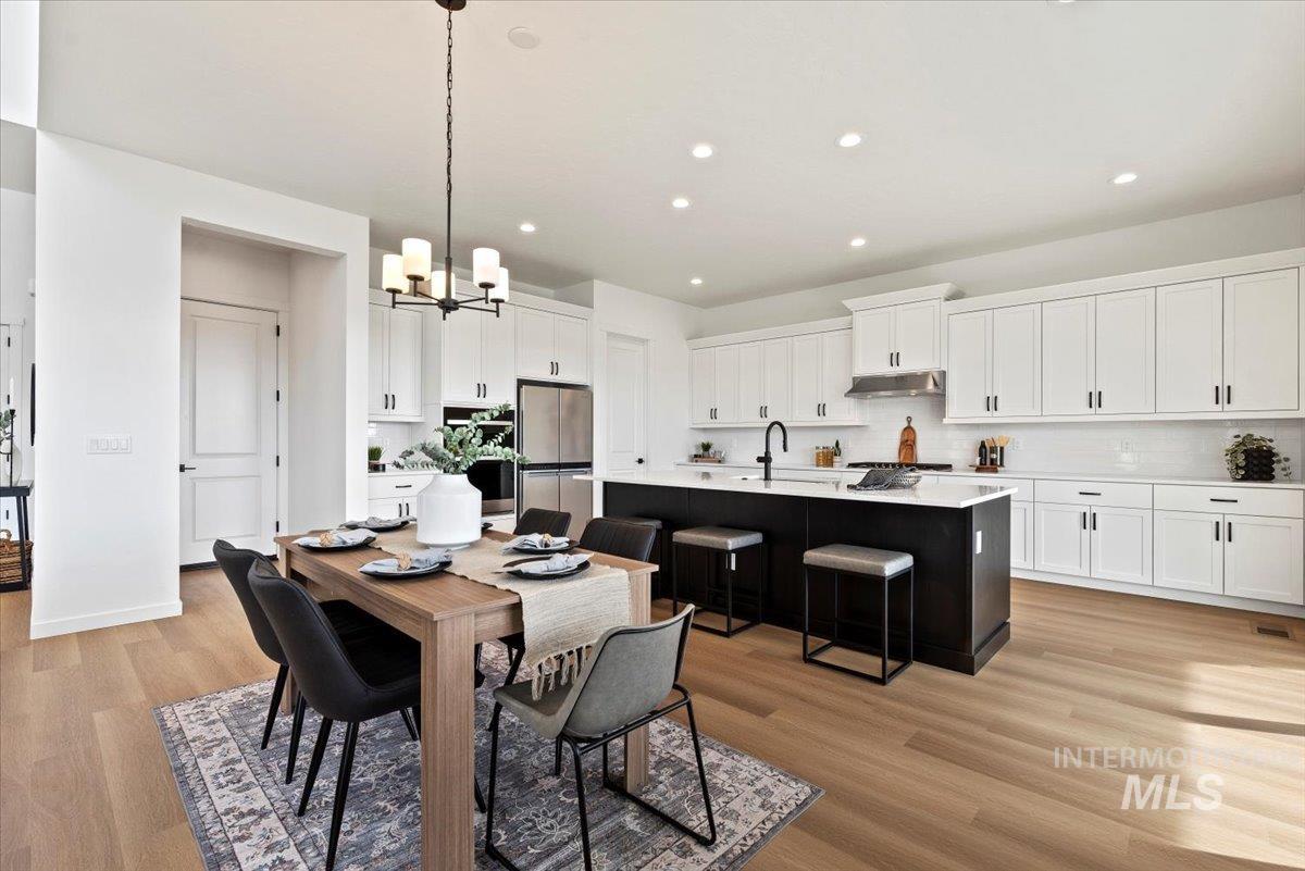 Dining area with light wood finished floors, recessed lighting, and a chandelier