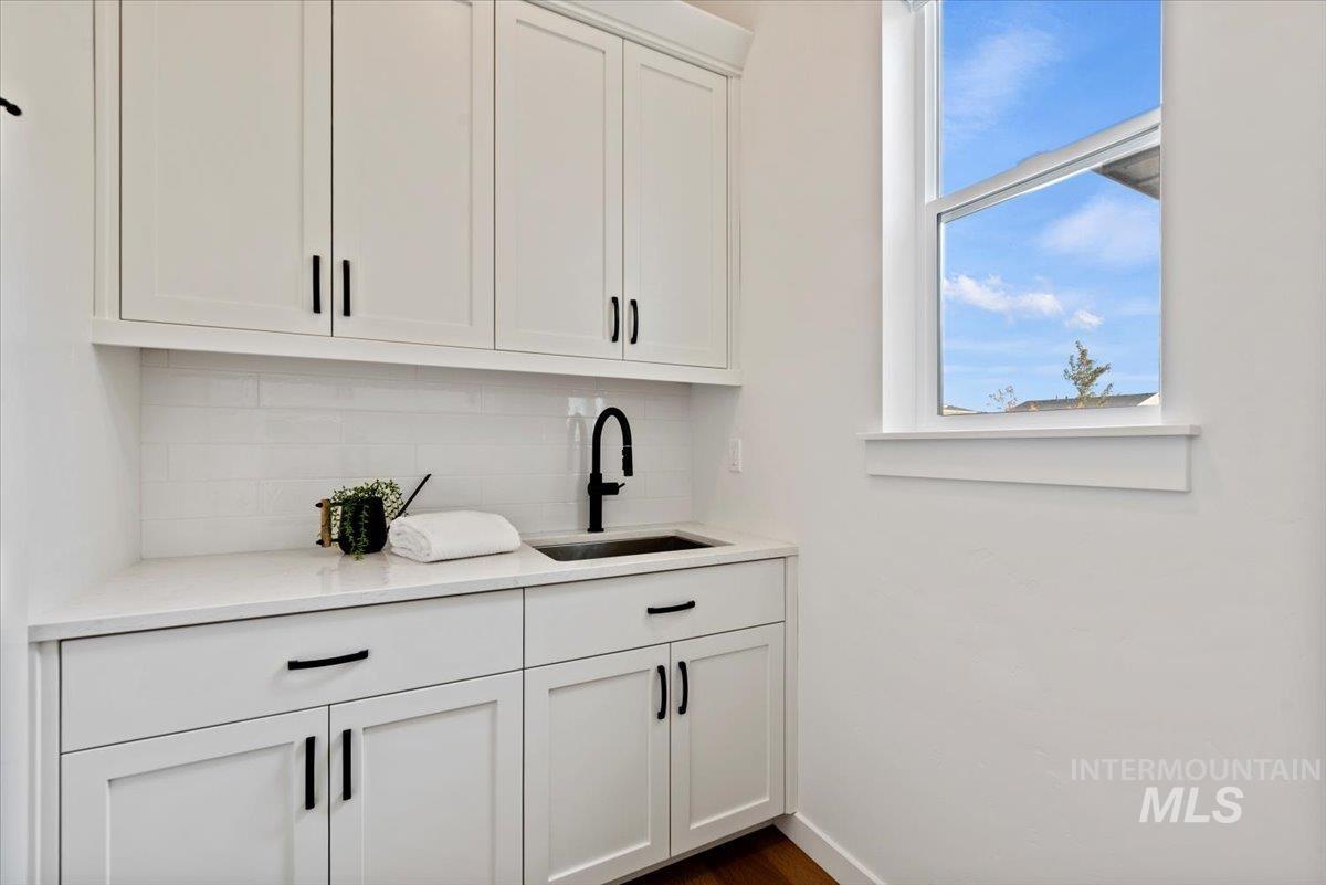 14701 Port Royal Street Caldwell, ID 83607 - Photo 21 of 40 Bar featuring white cabinetry, decorative backsplash, light stone countertops, and dark wood-style floors