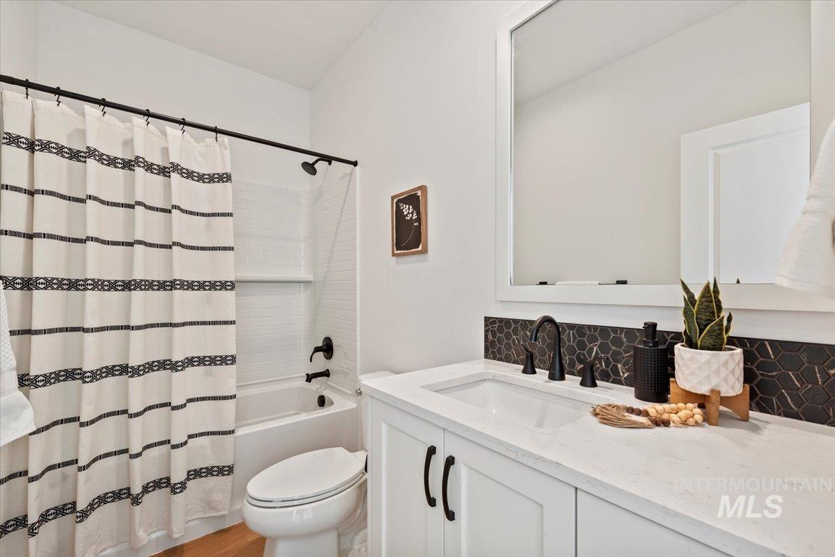 14701 Port Royal Street Caldwell, ID 83607 - Photo 28 of 40 Full bathroom featuring vanity, decorative backsplash, shower / tub combo, and light wood-style flooring