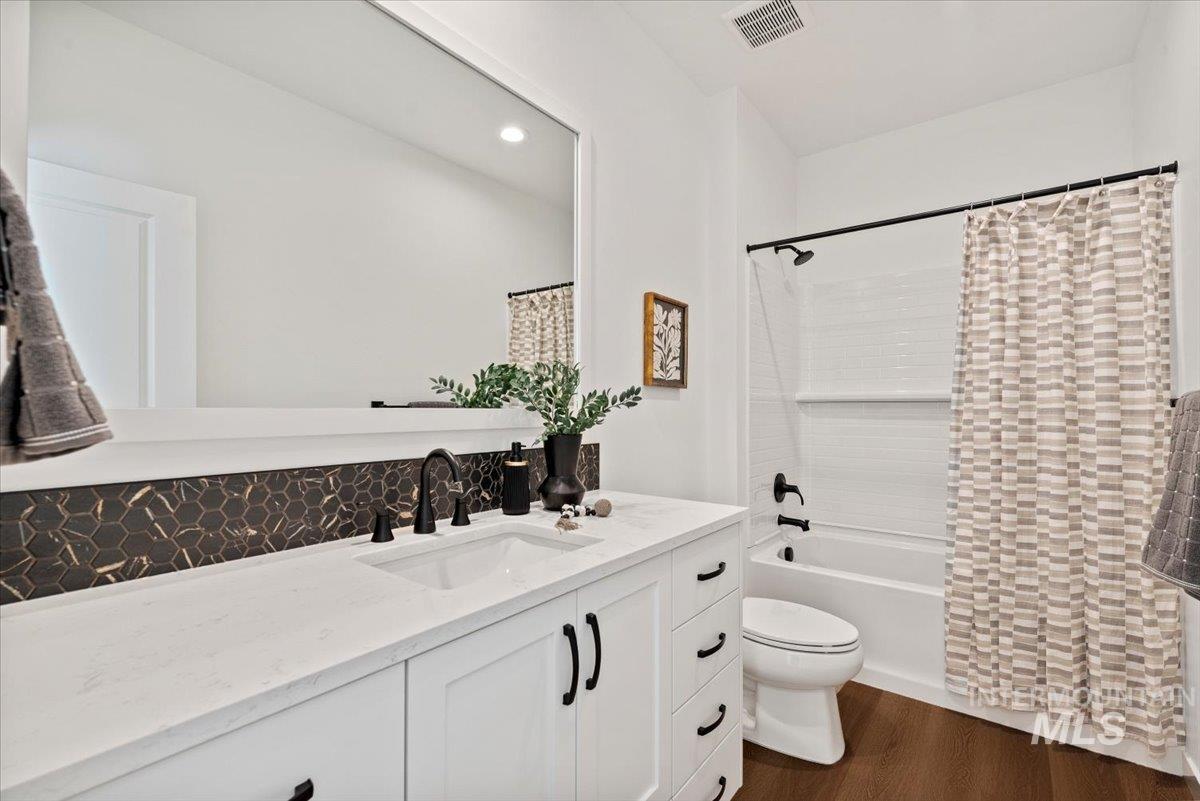 14701 Port Royal Street Caldwell, ID 83607 - Photo 29 of 40 Full bathroom featuring vanity, dark wood-type flooring, shower / bath combo with shower curtain, recessed lighting, and tasteful backsplash