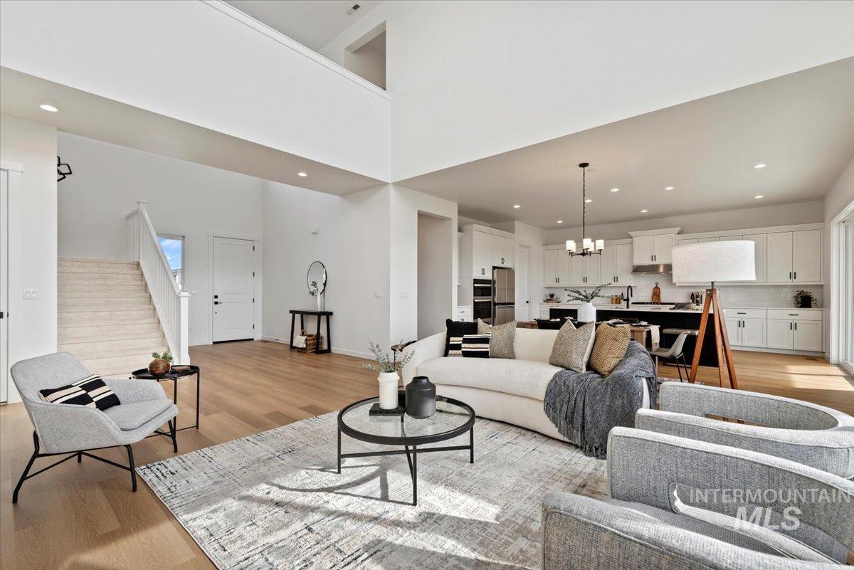 14701 Port Royal Street Caldwell, ID 83607 - Photo 6 of 40 Living room featuring stairway, light wood-type flooring, recessed lighting, a chandelier, and a high ceiling