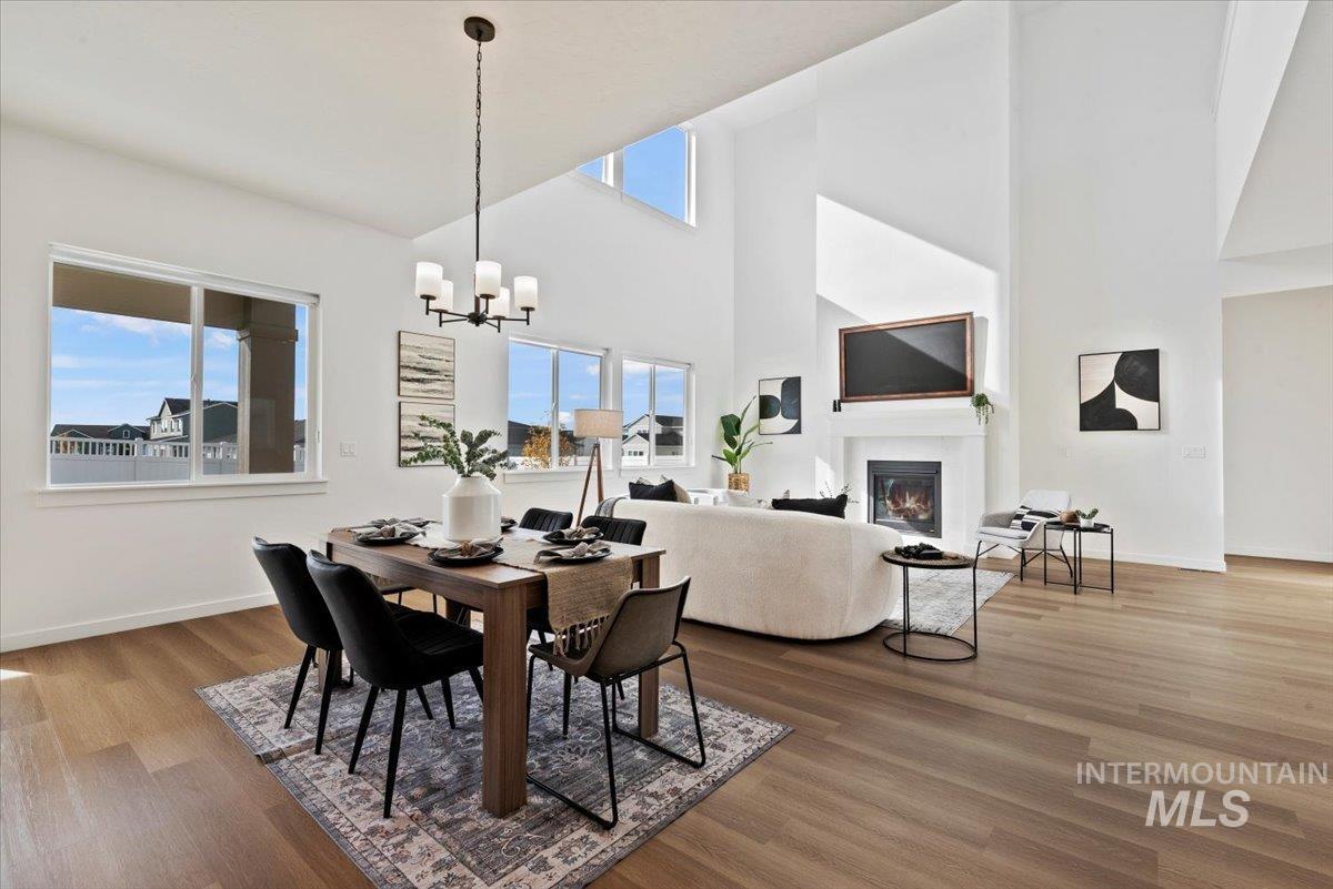 14701 Port Royal Street Caldwell, ID 83607 - Photo 8 of 40 Dining room with a glass covered fireplace, high vaulted ceiling, light wood-style flooring, and a chandelier