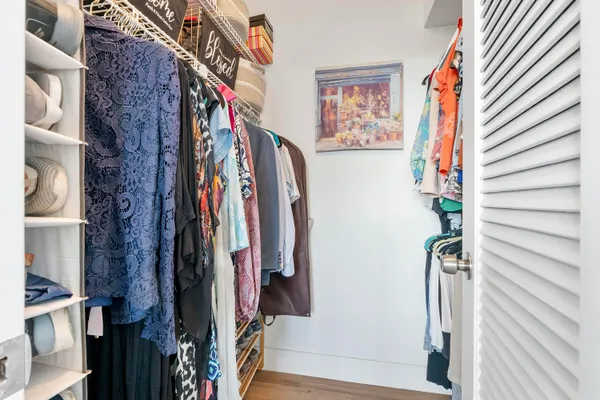 a view of walk in closet with clothes and shoes