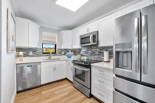 a kitchen with white cabinets appliances and sink
