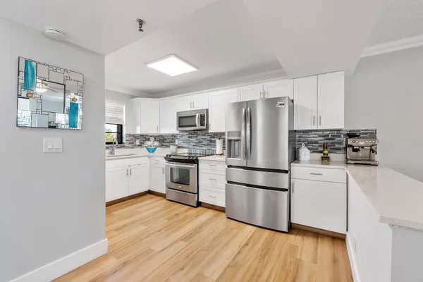 a kitchen with white cabinets stainless steel appliances and wooden floor