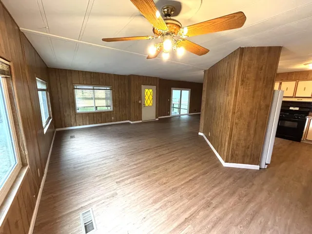 an empty room with wooden floor and windows