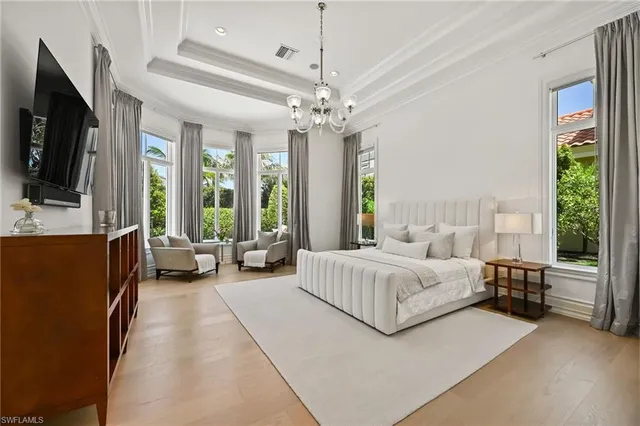 a spacious bedroom with a bed couch tv and window