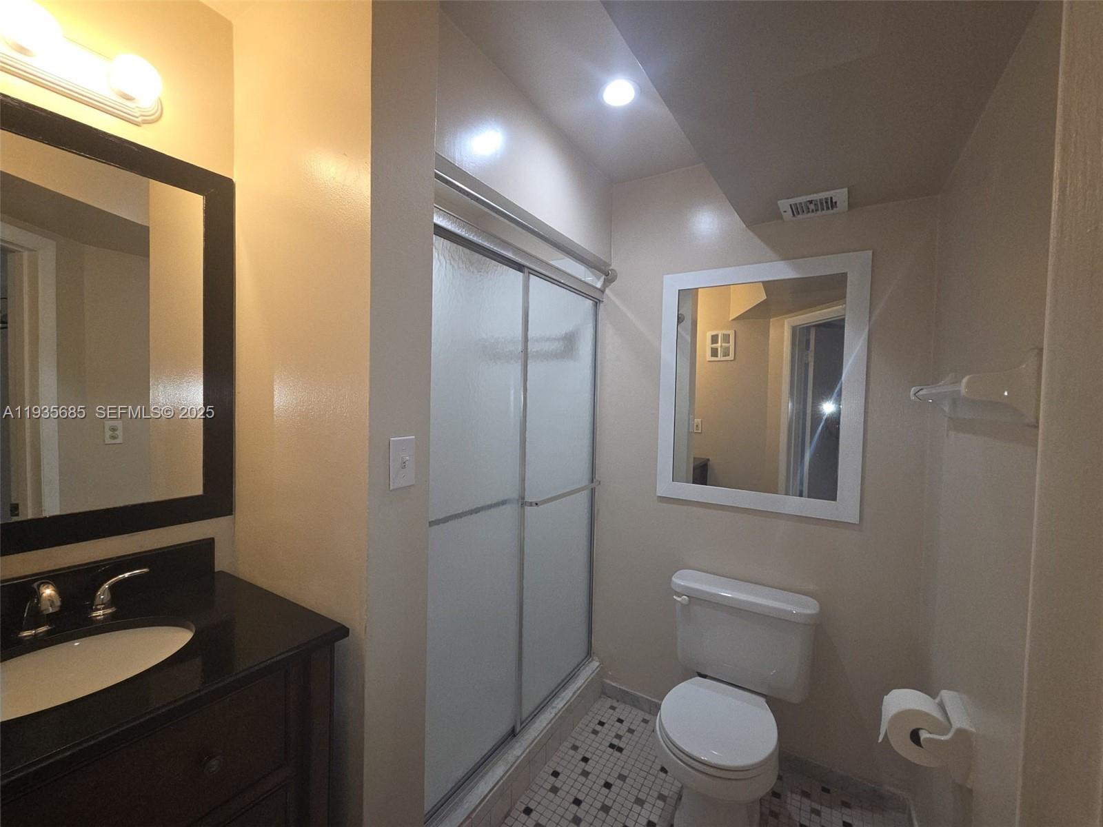 8020 North Colony Circle, Unit 305 Tamarac, FL 33321 - Photo 11 of 19 a bathroom with a toilet a sink a mirror and vanity