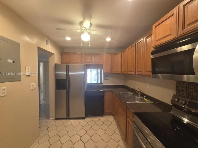 a kitchen with stainless steel appliances granite countertop a sink a stove a refrigerator a washer dryer and cabinets