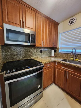 a kitchen with granite countertop wood cabinets stainless steel appliances and a sink