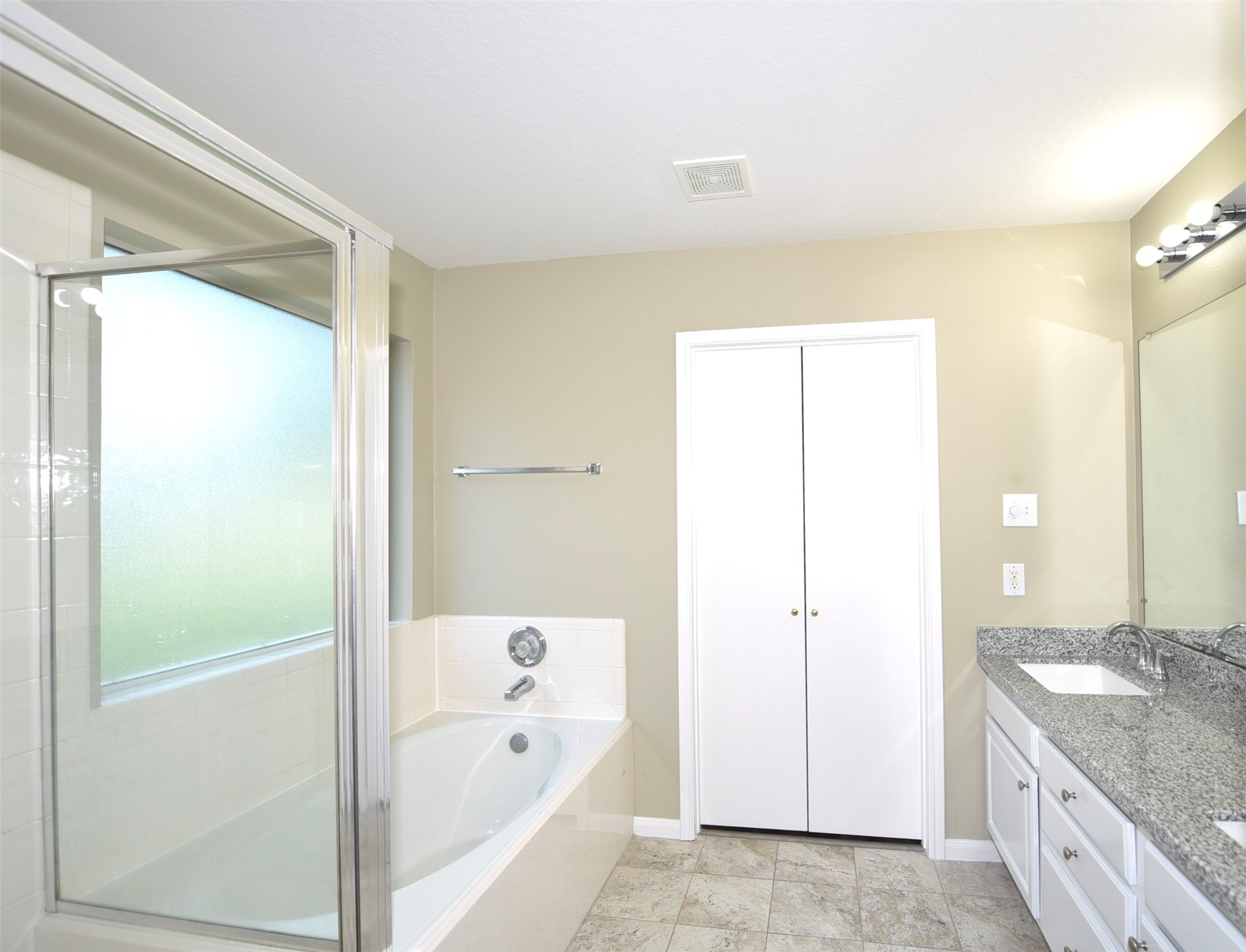 9611 Babbling Spring Court Tomball, TX 77375 - Photo 17 of 31 Bright bathroom with a frosted window, bathtub, separate shower, granite countertop, double sinks, and a spacious closet.