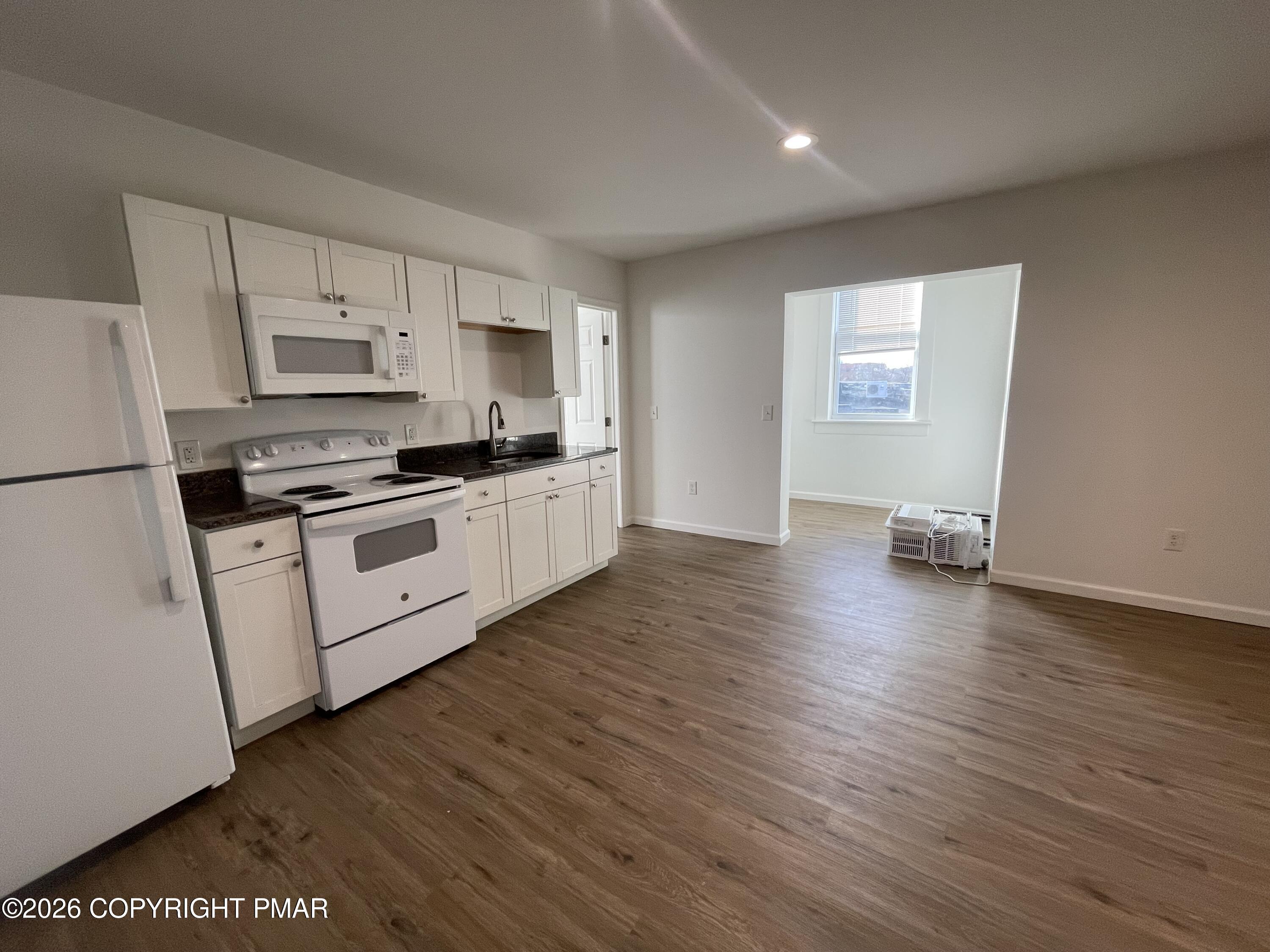 548 Main Street, Unit 6B Stroudsburg, PA 18360 - Photo 8 of 16 a kitchen with granite countertop a stove top oven a sink dishwasher and a refrigerator with wooden floor