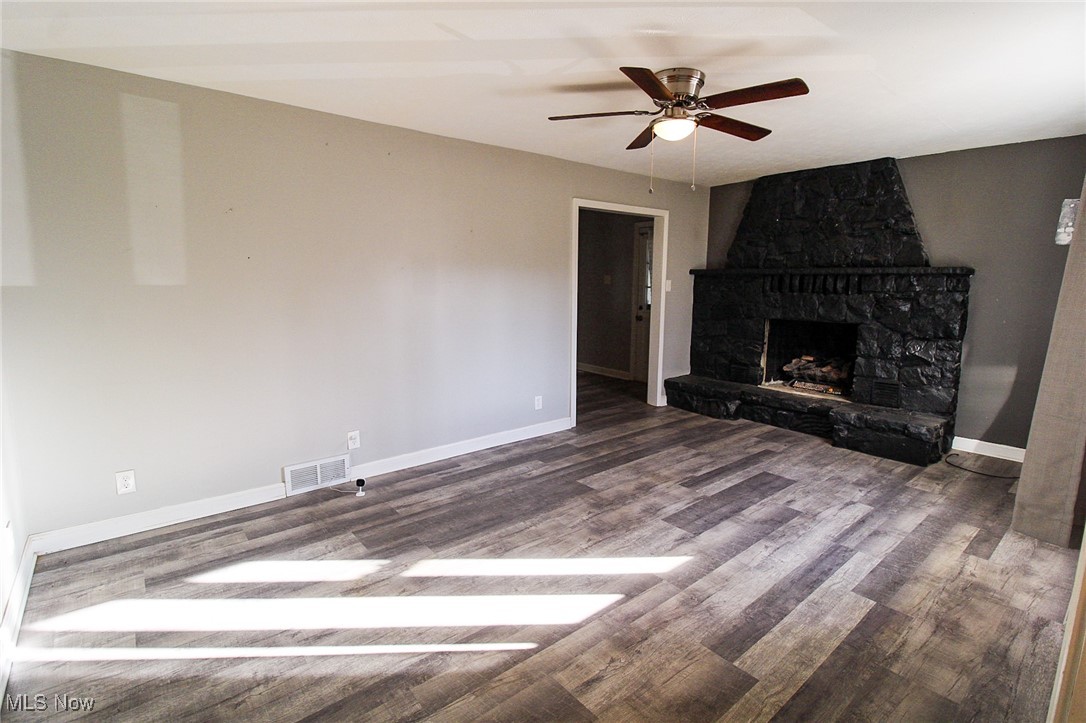 3267 South Leavitt Road Southwest Warren, OH 44481 - Photo 15 of 45 Unfurnished living room featuring dark wood finished floors, a fireplace, and ceiling fan