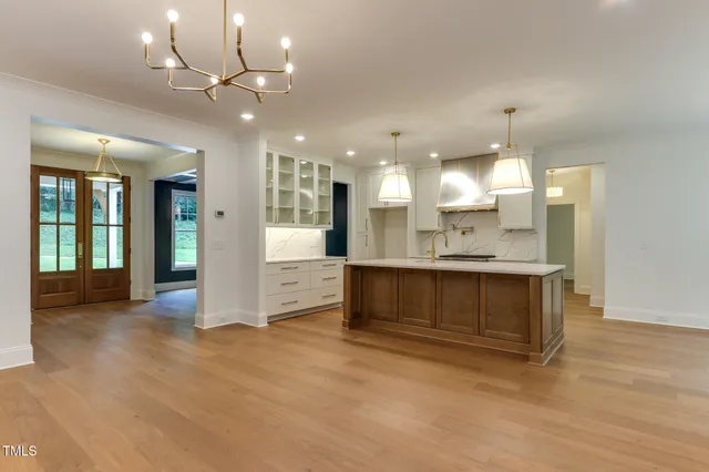 a view of an empty room with kitchen and window