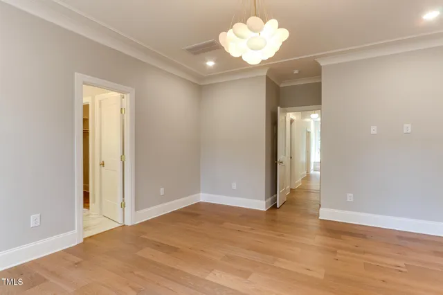 an empty room with wooden floor and hallway