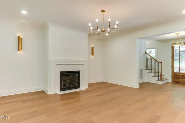 a view of an empty room with wooden floor fireplace and a window