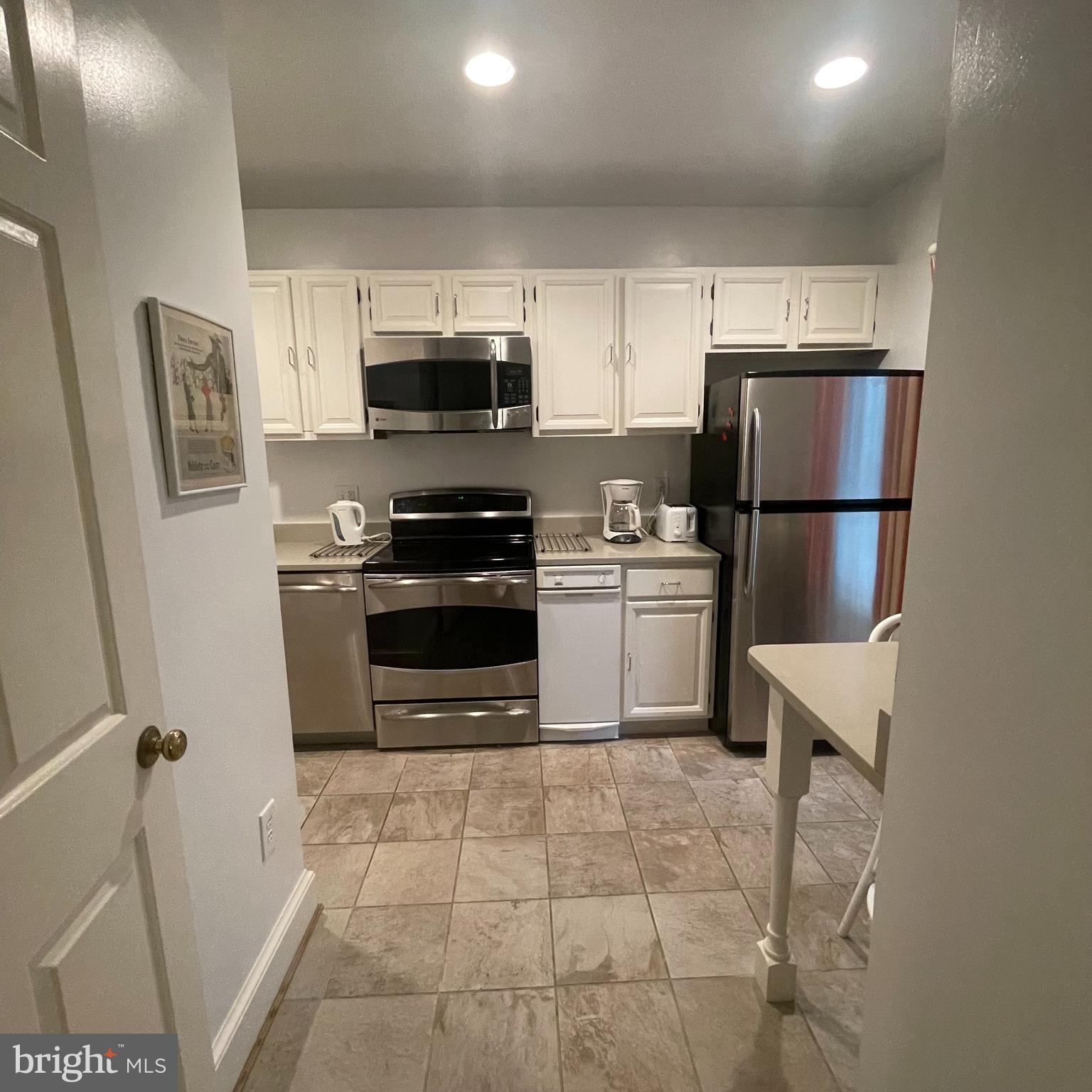 3221 Sutton Place Northwest, Unit B Washington, DC 20016 - Photo 8 of 22 a kitchen with a refrigerator a stove top oven and cabinets
