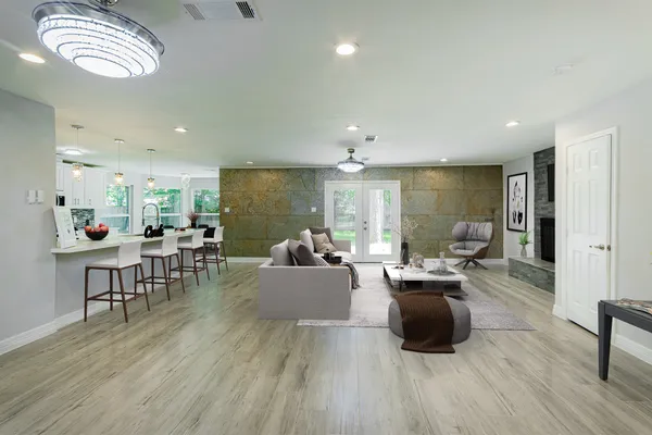 a living room with furniture kitchen view and a wooden floor