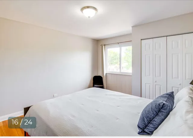 a bedroom with a bed and a lamp on dresser