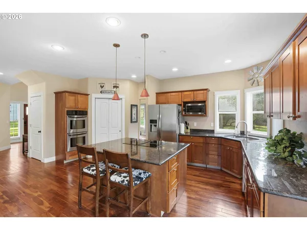 a kitchen with granite countertop a stove a sink a refrigerator and a living room view