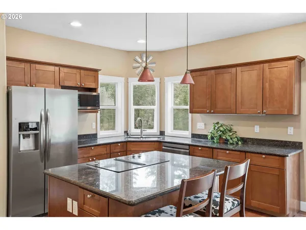 a kitchen with stainless steel appliances granite countertop a refrigerator a sink a stove and a cabinets