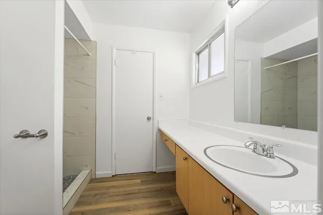a bathroom with a granite countertop sink a mirror and a shower