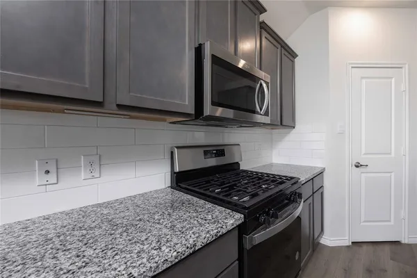 a kitchen with stainless steel appliances granite countertop a stove and a microwave