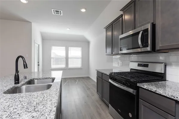 a kitchen with stainless steel appliances granite countertop a sink stove and microwave