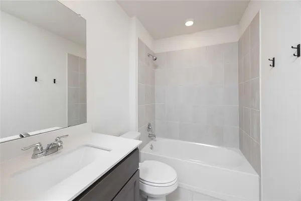 a bathroom with a bathtub shower sink vanity mirror and toilet
